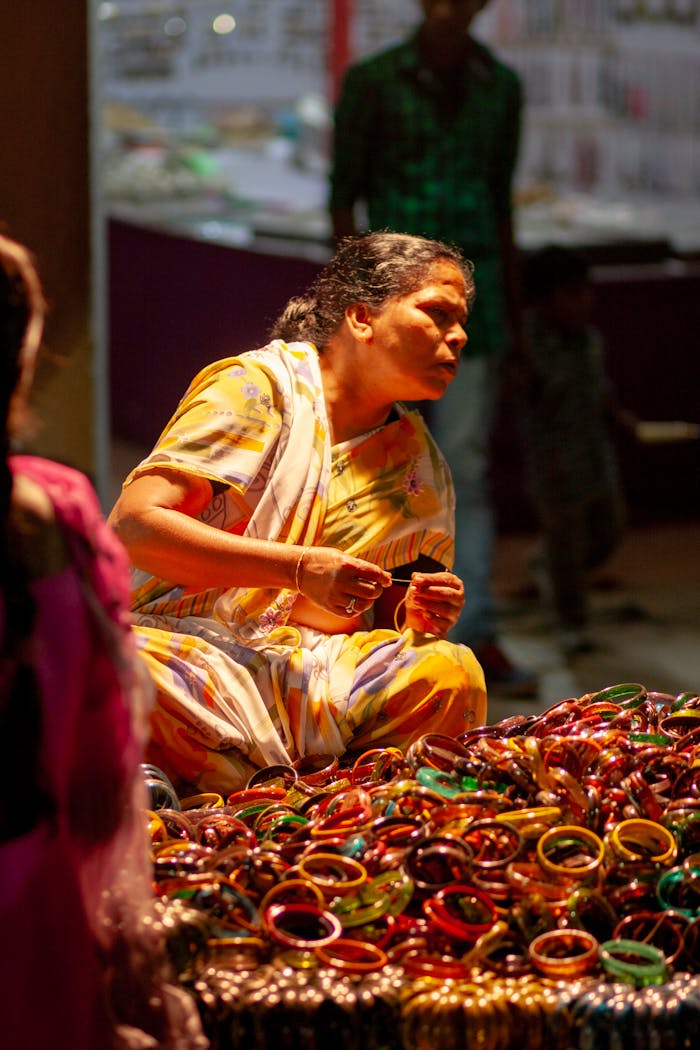 An Indian woman arranging colorful bangles in a busy Hyderabad bazaar, showcasing vibrant traditional clothing.